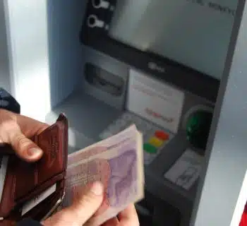 person holding brown leather wallet and banknotes