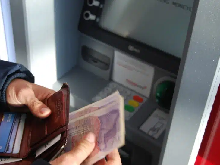 person holding brown leather wallet and banknotes