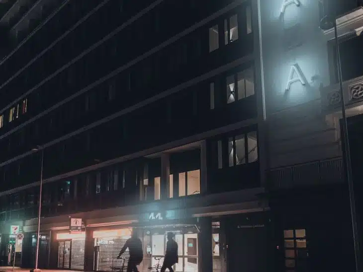 people walking on sidewalk near building during night time